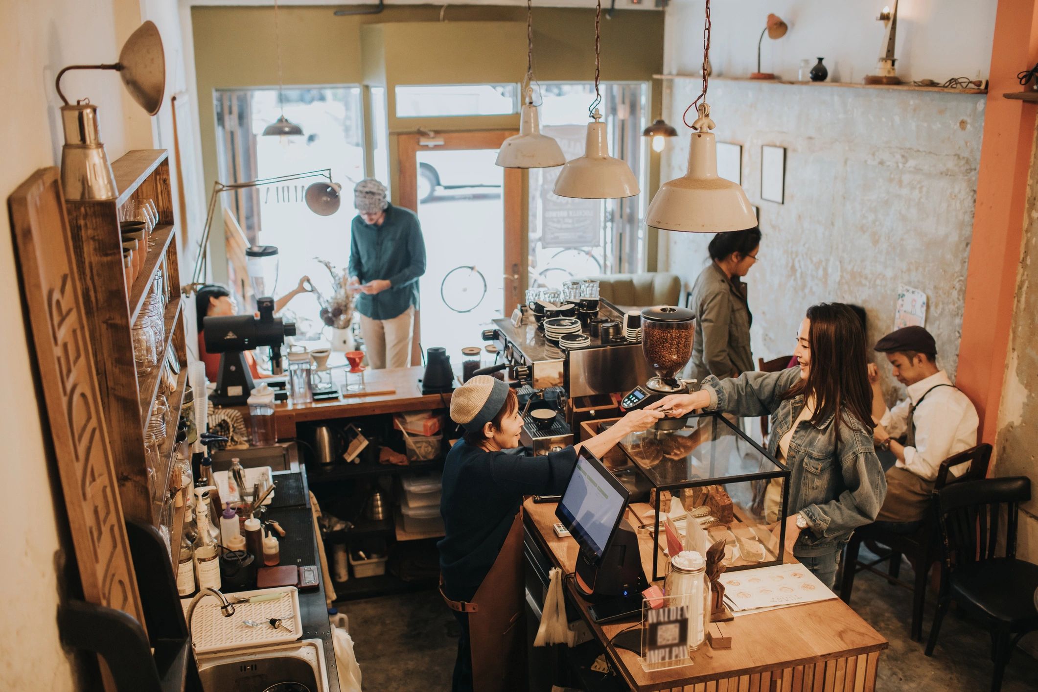 Barista serving a customer inside a welcoming coffee shop